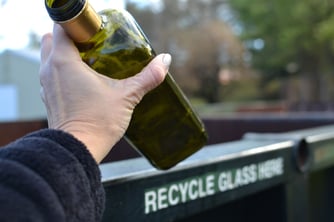 hand-putting-a-glass-bottle-in-a-recycling-contain-2022-11-14-03-40-18-utc