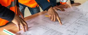 Plano arquitectónico y presupuesto sobre una mesa con casco y herramientas, simbolizando la planificación de un proyecto de construcción.